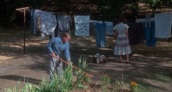 Movie still from “Stand by Me” (1986), directed by Rob Reiner – A man and a woman standing next to a basket of clothes; Wide shot, High angle