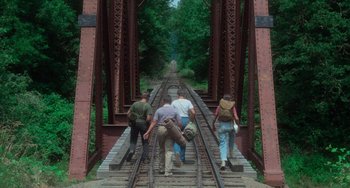 Movie still from “Stand by Me” (1986), directed by Rob Reiner – A group of people walking across train tracks; Wide shot, High angle