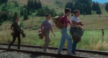 Movie still from “Stand by Me” (1986), directed by Rob Reiner – A group of people walking down a train track; Wide shot, Low angle