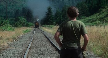 Movie still from “Stand by Me” (1986), directed by Rob Reiner – A man standing on the side of a train tracks; Wide shot, Over the shoulder angle