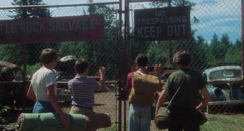 Movie still from “Stand by Me” (1986), directed by Rob Reiner – A group of people standing next to each other near a fence; Wide shot, Low angle