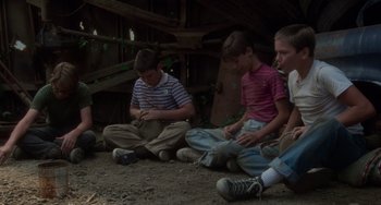Movie still from “Stand by Me” (1986), directed by Rob Reiner – A group of young people sitting on the ground; Wide shot, High angle