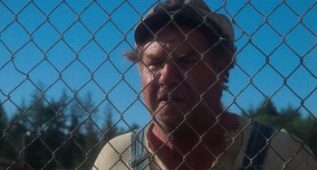 Movie still from “Stand by Me” (1986), directed by Rob Reiner – A man with a hat looking through a chain link fence; Close Up shot, Over the shoulder angle