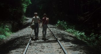 Movie still from “Stand by Me” (1986), directed by Rob Reiner – Two people walking along a train track in the woods; Wide shot, High angle