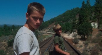 Movie still from “Stand by Me” (1986), directed by Rob Reiner – Two young men standing on a train track; Medium shot, Low angle