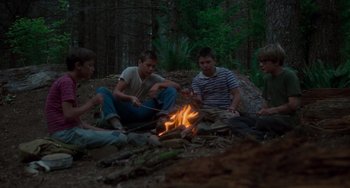 Movie still from “Stand by Me” (1986), directed by Rob Reiner – A group of young men sitting around a campfire; Wide shot, High angle