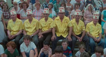 Movie still from “Stand by Me” (1986), directed by Rob Reiner – A group of men and women sitting in front of a group of people; Wide shot, High angle