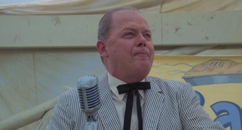 Movie still from “Stand by Me” (1986), directed by Rob Reiner – A man in a striped jacket and bow tie is holding a microphone; Close Up shot, Low angle