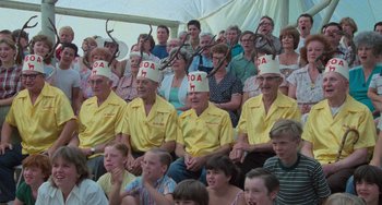 Movie still from “Stand by Me” (1986), directed by Rob Reiner – A group of people sitting in a crowd wearing hats; Medium shot, High angle