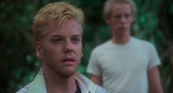 Movie still from “Stand by Me” (1986), directed by Rob Reiner – A man with blonde hair standing next to another man; Close Up shot, Over the shoulder angle