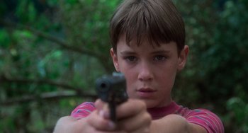 Movie still from “Stand by Me” (1986), directed by Rob Reiner – A young boy is holding a gun in his hand; Close Up shot, Low angle
