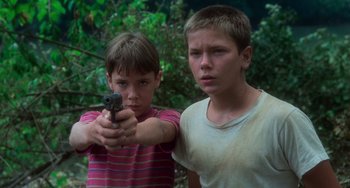 Movie still from “Stand by Me” (1986), directed by Rob Reiner – Two young boys are holding a gun in their hands; Close Up shot, Low angle