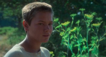 Movie still from “Stand by Me” (1986), directed by Rob Reiner – A young man is standing in front of some plants; Close Up shot, Low angle