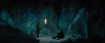 Movie still from “Star Trek” (2009), directed by J.J. Abrams – A man is holding a torch in a cave with a man sitting on the ground; Wide shot, High angle