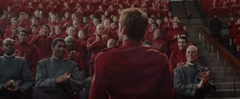 Movie still from “Star Trek” (2009), directed by J.J. Abrams – A crowd of people in red suits clapping in front of a man; Medium shot, Over the shoulder angle