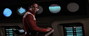 Movie still from “Star Trek II: The Wrath of Khan” (1982), directed by Nicholas Meyer – A man in a red and white uniform holding a computer keyboard; Medium shot, Low angle
