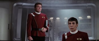 Movie still from “Star Trek II: The Wrath of Khan” (1982), directed by Nicholas Meyer – A man in a red and white uniform standing next to a woman; Medium shot, Over the shoulder angle