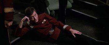 Movie still from “Star Trek II: The Wrath of Khan” (1982), directed by Nicholas Meyer – A man dressed in a red suit sitting on the ground; Medium shot, High angle
