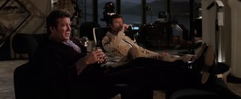 Movie still from “Star Trek II: The Wrath of Khan” (1982), directed by Nicholas Meyer – Two men are sitting in a chair and one is drinking a beverage; Medium shot, Low angle