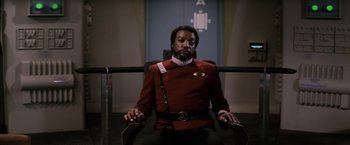 Movie still from “Star Trek II: The Wrath of Khan” (1982), directed by Nicholas Meyer – A man sitting in a chair wearing a red uniform; Medium shot, Low angle
