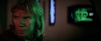 Movie still from “Star Trek II: The Wrath of Khan” (1982), directed by Nicholas Meyer – A person with green hair is in front of a television; Close Up shot, Over the shoulder angle