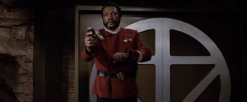 Movie still from “Star Trek II: The Wrath of Khan” (1982), directed by Nicholas Meyer – A man in a star trek uniform holding a cell phone; Medium shot, Low angle