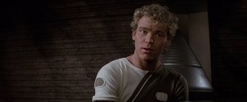 Movie still from “Star Trek II: The Wrath of Khan” (1982), directed by Nicholas Meyer – A young man with blonde curly hair wearing a white t - shirt; Close Up shot, Over the shoulder angle