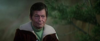 Movie still from “Star Trek II: The Wrath of Khan” (1982), directed by Nicholas Meyer – An older man wearing a green shirt and a brown jacket; Close Up shot, Over the shoulder angle