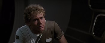 Movie still from “Star Trek II: The Wrath of Khan” (1982), directed by Nicholas Meyer – A man with curly blonde hair wearing a brown t - shirt; Close Up shot, Over the shoulder angle
