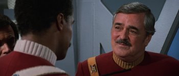 Movie still from “Star Trek III: The Search for Spock” (1984), directed by Leonard Nimoy – A man in a red and yellow uniform talking to another man in a red and yellow uniform; Close Up shot, Over the shoulder angle