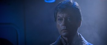 Movie still from “Star Trek III: The Search for Spock” (1984), directed by Leonard Nimoy – An older man in a dark room looking at the camera; Close Up shot, Low angle