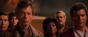 Movie still from “Star Trek III: The Search for Spock” (1984), directed by Leonard Nimoy – A man standing next to two other people in front of a wall; Close Up shot, Over the shoulder angle