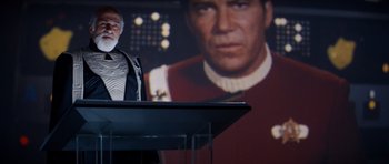 Movie still from “Star Trek IV: The Voyage Home” (1986), directed by Leonard Nimoy – A man standing in front of a screen with a star trek picture behind him; Medium shot, Over the shoulder angle