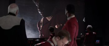 Movie still from “Star Trek IV: The Voyage Home” (1986), directed by Leonard Nimoy – A group of men in red shirts standing next to each other in front of a screen; Medium shot, Over the shoulder angle