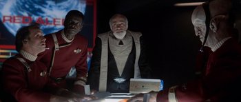 Movie still from “Star Trek IV: The Voyage Home” (1986), directed by Leonard Nimoy – A man in a star trek costume standing in front of a table; Medium shot, Over the shoulder angle