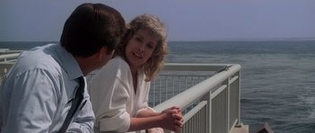 Movie still from “Star Trek IV: The Voyage Home” (1986), directed by Leonard Nimoy – A woman sitting next to a man on top of a railing near the ocean; Medium shot, Over the shoulder angle