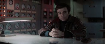 Movie still from “Star Trek IV: The Voyage Home” (1986), directed by Leonard Nimoy – A man sitting at a table in front of an electrical panel; Medium shot, Low angle