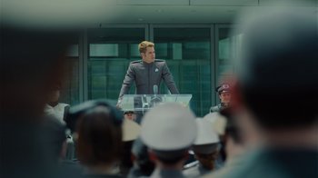 Movie still from “Star Trek Into Darkness” (2013), directed by J.J. Abrams – A man is standing at a podium in front of a group of people; Medium shot, Over the shoulder angle