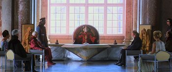 Movie still from “Star Wars: Episode I - The Phantom Menace” (1999), directed by George Lucas – A woman sitting on top of a round table in front of three other people; Wide shot, Low angle