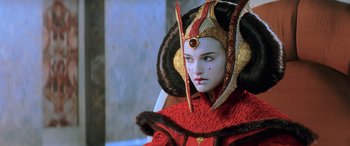 Movie still from “Star Wars: Episode I - The Phantom Menace” (1999), directed by George Lucas – A woman in a red dress and a red and gold headpiece; Close Up shot, Over the shoulder angle
