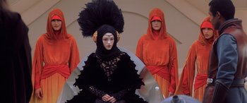 Movie still from “Star Wars: Episode I - The Phantom Menace” (1999), directed by George Lucas – A group of people in costumes on a stage; Medium shot, Over the shoulder angle