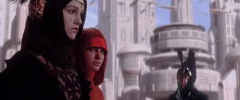 Movie still from “Star Wars: Episode I - The Phantom Menace” (1999), directed by George Lucas – Two women in red are standing next to each other in front of a building; Close Up shot, Low angle