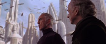 Movie still from “Star Wars: Episode I - The Phantom Menace” (1999), directed by George Lucas – Two older men standing next to each other in front of a city; Medium shot, Low angle