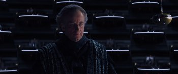 Movie still from “Star Wars: Episode I - The Phantom Menace” (1999), directed by George Lucas – An older man in a dark room looking at the camera; Medium shot, Over the shoulder angle