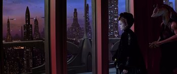 Movie still from “Star Wars: Episode I - The Phantom Menace” (1999), directed by George Lucas – A woman standing in front of a window looking out at a city skyline; Wide shot, Low angle