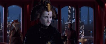 Movie still from “Star Wars: Episode I - The Phantom Menace” (1999), directed by George Lucas – A woman in a black dress and a gold hat; Close Up shot, Over the shoulder angle