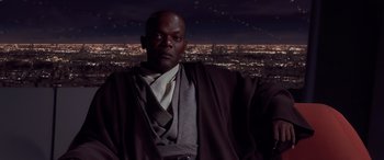 Movie still from “Star Wars: Episode I - The Phantom Menace” (1999), directed by George Lucas – A man in a robe and tie in front of a city skyline at night; Medium shot, High angle