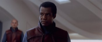 Movie still from “Star Wars: Episode I - The Phantom Menace” (1999), directed by George Lucas – A man wearing a leather jacket looking at the camera; Close Up shot, Over the shoulder angle