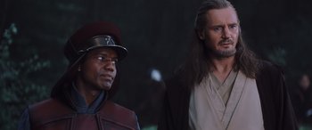 Movie still from “Star Wars: Episode I - The Phantom Menace” (1999), directed by George Lucas – A man standing next to another man wearing a hat; Close Up shot, Over the shoulder angle