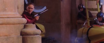 Movie still from “Star Wars: Episode I - The Phantom Menace” (1999), directed by George Lucas – A woman holding a large metal object in her hands; Medium shot, Low angle